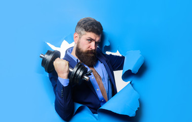 Businessman with dumbbell looking through paper hole. Power. Strength. Sport. Sporty bearded man...