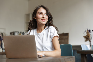Fototapeta premium Image of smiling attractive woman using laptop while sitting