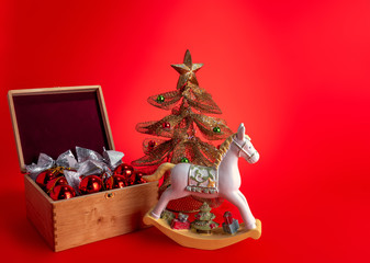 Festive composition with Christmas toys and a horse on a red background.
