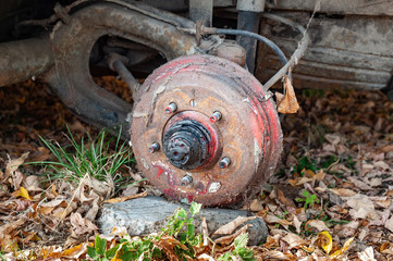 Old rusty dirty brake drum and suspension details of a broken car.