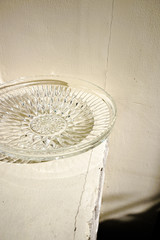 Crystal plate on weathered white wall background. high contrast and shadow 