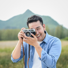 Asian photographer with vintage camera taking pictures in nature, lifestyle concept.