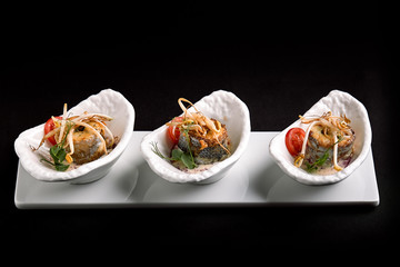 rolls of sea bass baked stuffed with vegetables and mushroom sauce, on a dark background, copy space