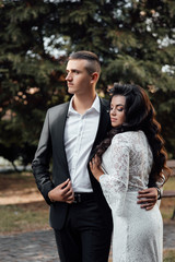 The guy in the suit and the girl in white dress embracing. A man and woman who loved each other. A love story. Romantic moment. Young beautiful couple in love, love, pre-wedding photo shoot.