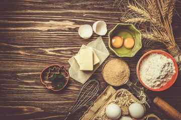 Baking concept - baking ingredients butter, flour, sugar, eggs on rustic wood background, top view