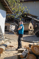 Man cut with saw. Dust and movements. Woodcutter saws tree with chainsaw on sawmill. lumberjack