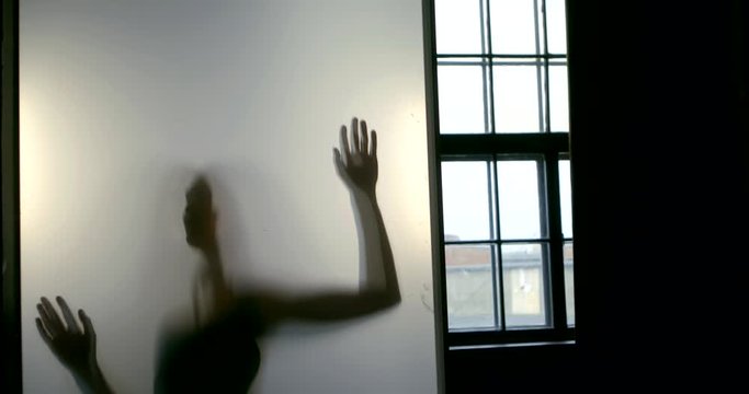 Closeup of the shadow hands and the silhouette of the female slender body with large Breasts reflected in the glass near the window.