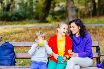 Fototapeta premium Happy mother with two laughing smiling emotional two children at autmn park.