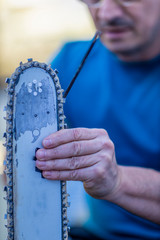Sharpening a chainsaw Close up on a man sharpening a chainsaw chain with file