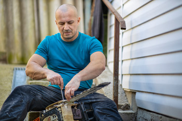 Sharpening a chainsaw Close up on a man sharpening a chainsaw chain with file