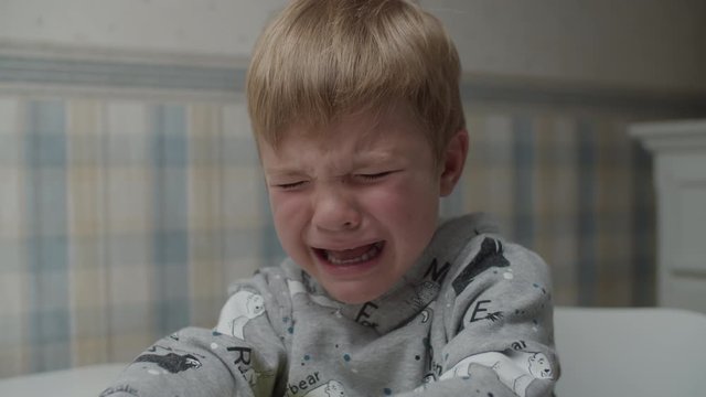 Upset blonde boy crying with emotions on his face in slow motion. Weeping child is unhappy. 