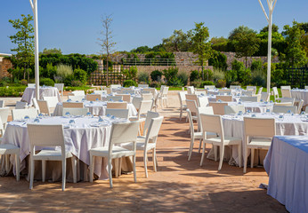 Wedding banquet tables preparing for a wedding outside on a summer day.