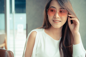 portrait of beautiful Asian women wear sunglasses and sitting in a coffee shop.