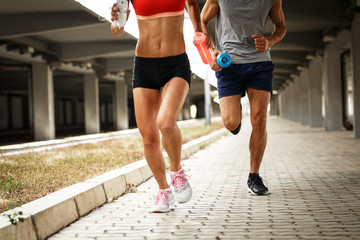 Couple of runners jogging on the city street under the bridge.