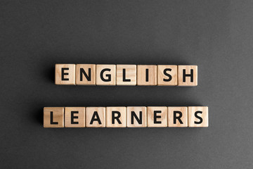 English learners - phrase from wooden blocks with letters, students  english learners concept, top...