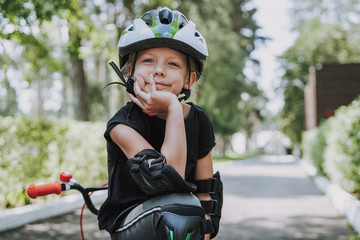 Fototapeta na wymiar Cute little girl in bicycle helmet spending time outdoors