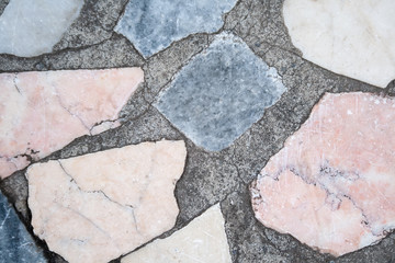 Concrete surface with multiple patches of large colored stones. Closeup