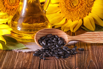 Rural still-life - the sunflower oil in glass cruet with flowers of sunflower (Helianthus annuus)...