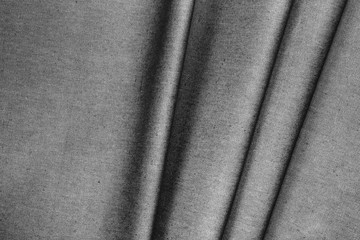 Fototapeta premium Gray woolen folded fabric with folds and waves, closeup, background of the folded fabric