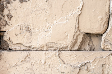 Old rough beige painted wall with cracks and holes