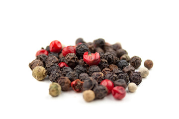 A mix of four types of pepper grain: black, white, pink, green. Isolated on white background. Selective focus. Closeup view