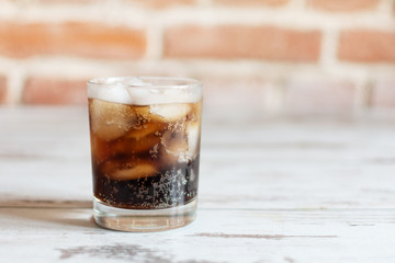 Cold fizzy cola soda with ice cubes in glass.