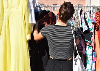 A young woman chooses a dress in a flea market