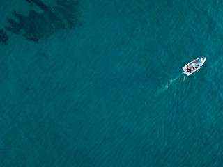 Aerial view of a rowing boat seen from above, powered by an engine. Blue sea that surrounds a boat that crosses it. People inside a boat. 10/22/2019. Pizzo Calabro, Calabria, Italy