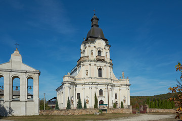 Fototapeta na wymiar Roman Catholic Church of Holy Trinity in Mykulyntsi, Ternopil Oblast, Ukraine, 49.39972, 25.60621. Stone religious building of Christian Cathedral of baroque style.