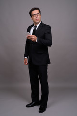 Obraz na płótnie Canvas Full body shot of handsome Persian businessman using phone