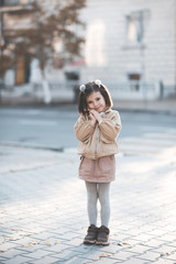 Cute kid girl 3-4 year old wearing trendy clothes posing in cityoutdoors. Looking at camera. Childhood. Autumn season.