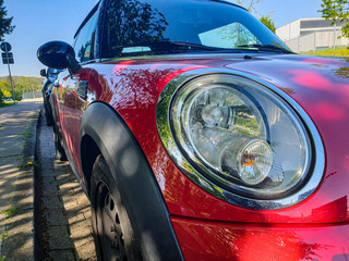 Fototapeta premium The front of the car is a close-up. Car headlight. red car