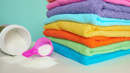 pink plastic measuring vessel with washing powder, containers with detergent, stack terry towels