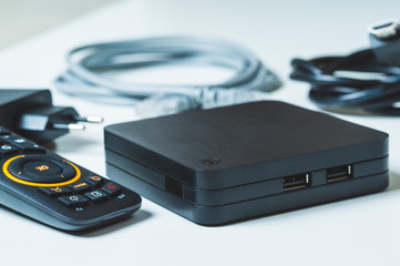 TV set-top box and all the necessary wires to connect it on a white background, selective focusing