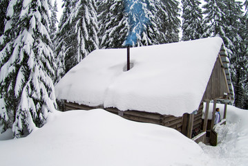 little house in winter mountains amidst snow-covered forest