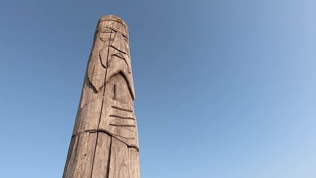 Wooden idol Slavic god Svarog on a background of blue sky