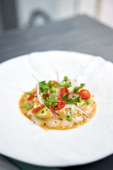 Tartar from scallop with avocado, cherry tomatoes, radishes and onion. Dish in the restaurant from raw seafood.