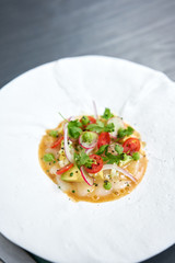 Tartar from scallop with avocado, cherry tomatoes, radishes and onion. Dish in the restaurant from raw seafood.