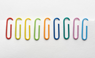 Different colors of paper clips hold white paper