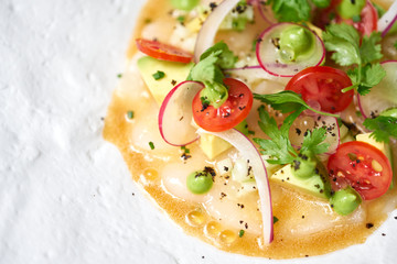 Tartar from scallop with avocado, cherry tomatoes, radishes and onion. Dish in the restaurant from raw seafood.