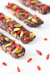 Vegan chocolate bars with granola, nuts, pumpkin and chia seeds. Homemade snack. Super energy bars on a white wooden background.