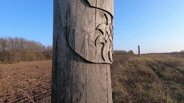 Wooden idol Slavic god Svarog on a background of blue sky