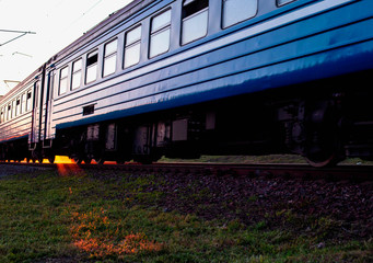 Obraz premium The train travels by rail against the background of the rays of the sun. International passenger train schedule concept, copy space