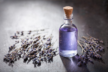 Glass bottle of lavender essential oil with dried lavender flowers