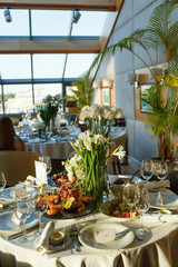 Glass vases with white flowers (tulips, irises, roses) on the festive table. Decor of wedding tables at a banquet