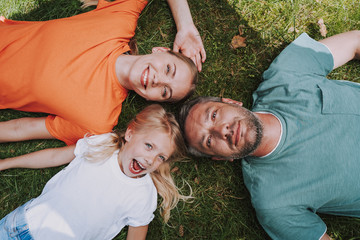 Happy parents and their daughter lying on green grass