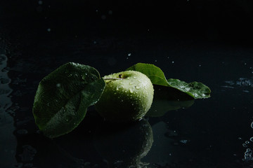  green apple in spray of water or dew on a black background. The concept of a healthy lifestyle or good nutrition, vegetarianism