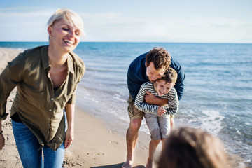 Young family with two small children outdoors on beach, having fun.
