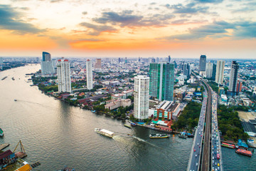 Fototapeta premium Sunset with modern building and transport city road aerial view