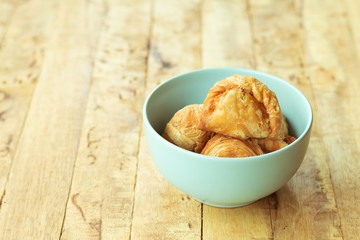 Curry puff pastry in cyan vintage bowl put on old table with copy-space